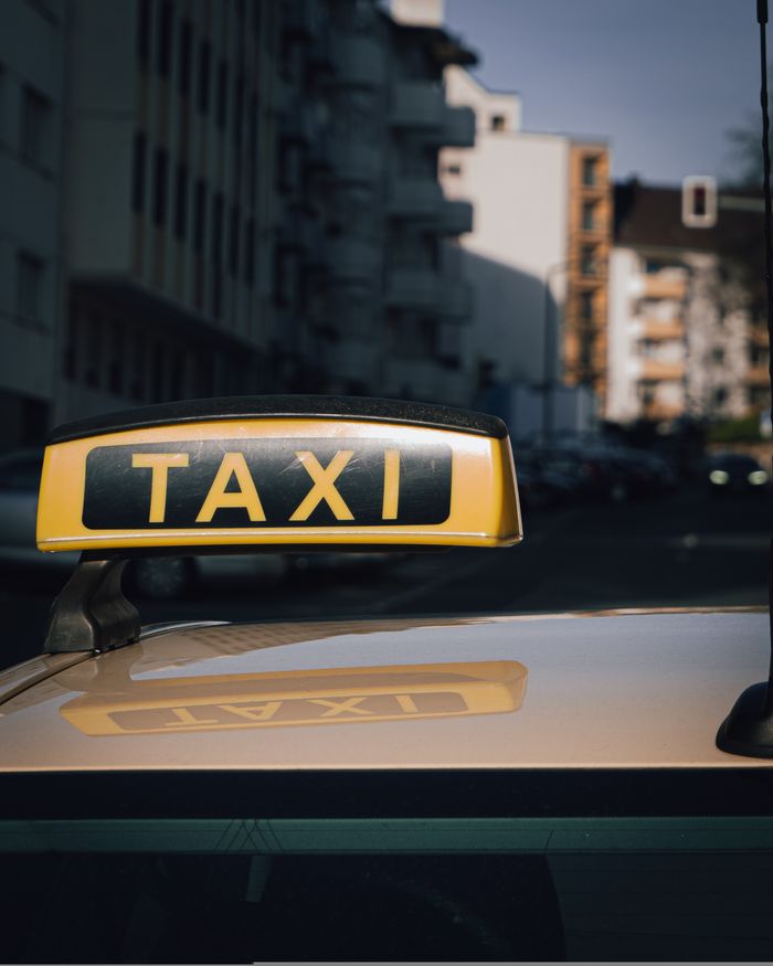 Services Close-up of a taxi sign on a car roof with an urban city background.