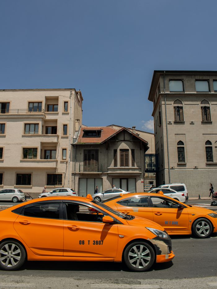 Street view of yellow taxis in front of historic buildings under clear blue sky.