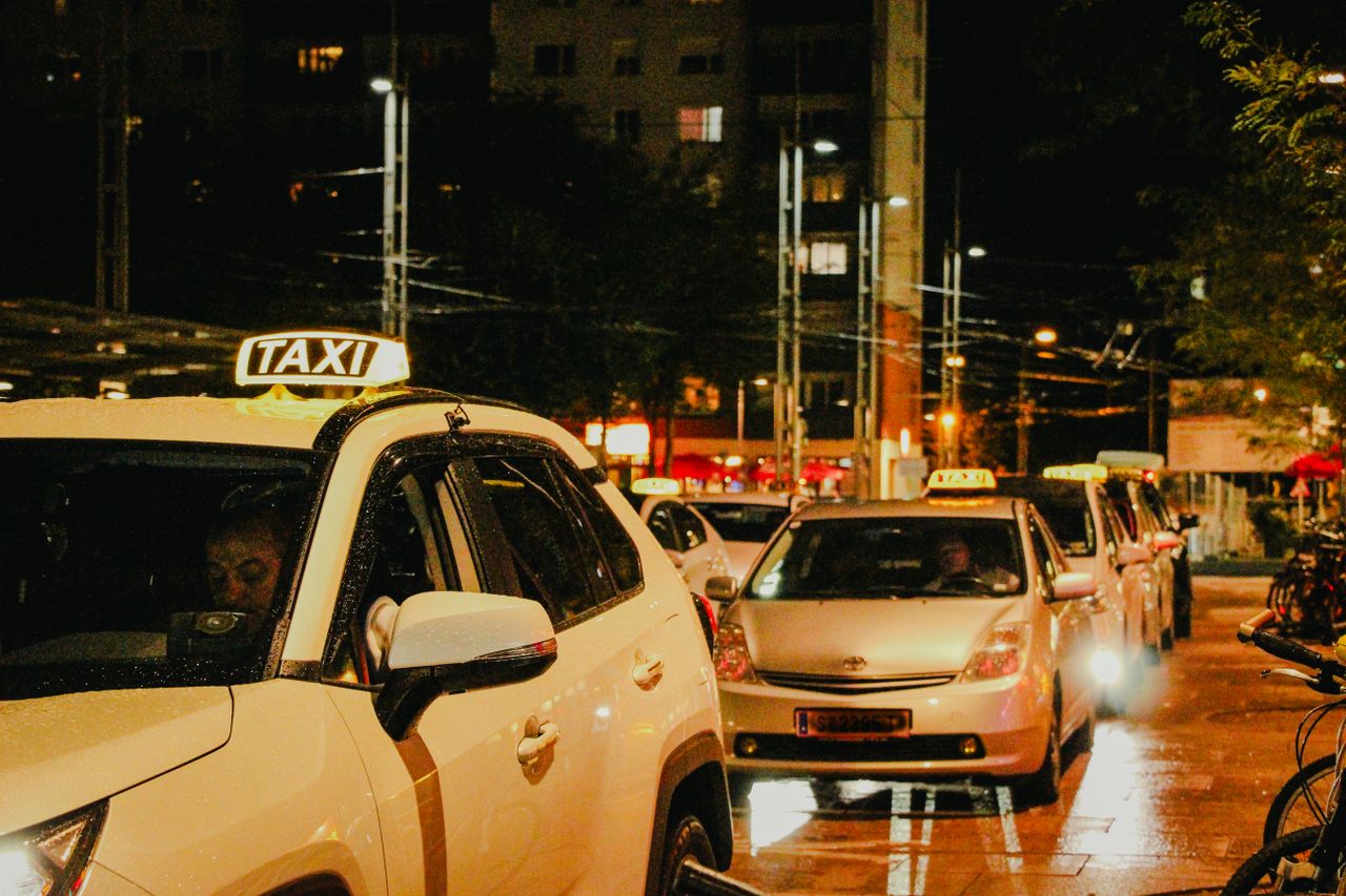 Taxis lined up under streetlights in Salzburg, Austria, captured at night.