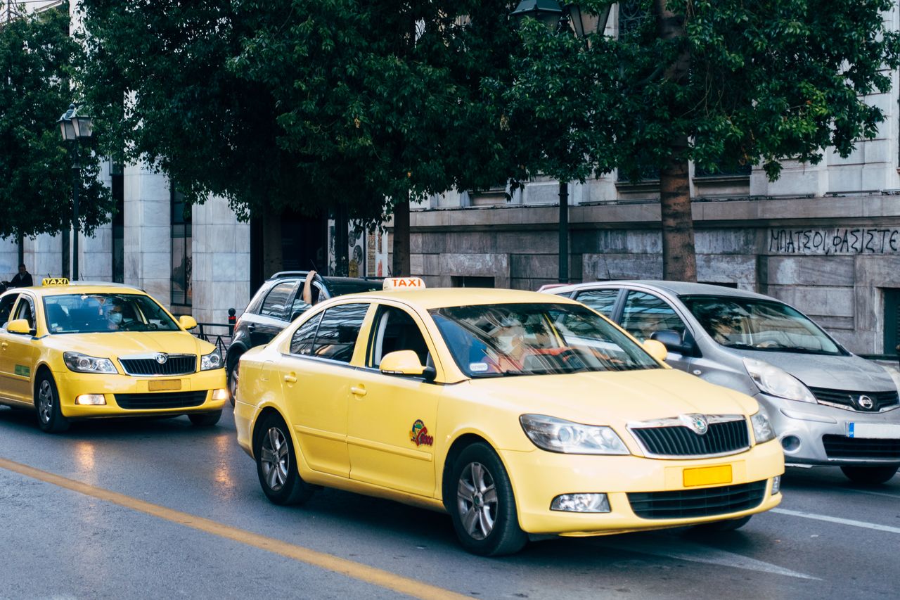 Services Yellow taxis lining the street in Athens, Greece, showcasing city's bustling transportation.