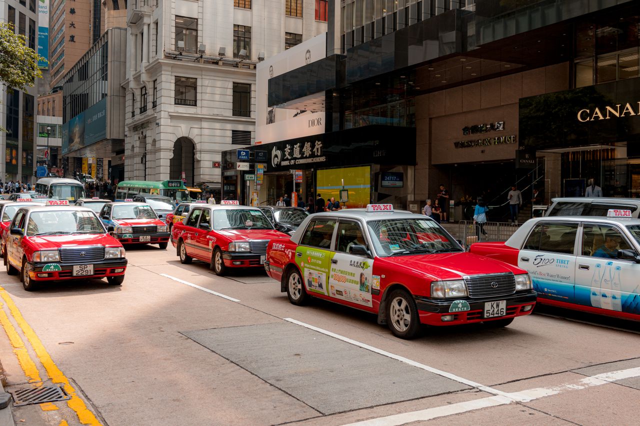 Services Bustling city street with red taxis and busy shops in downtown on a sunny day.